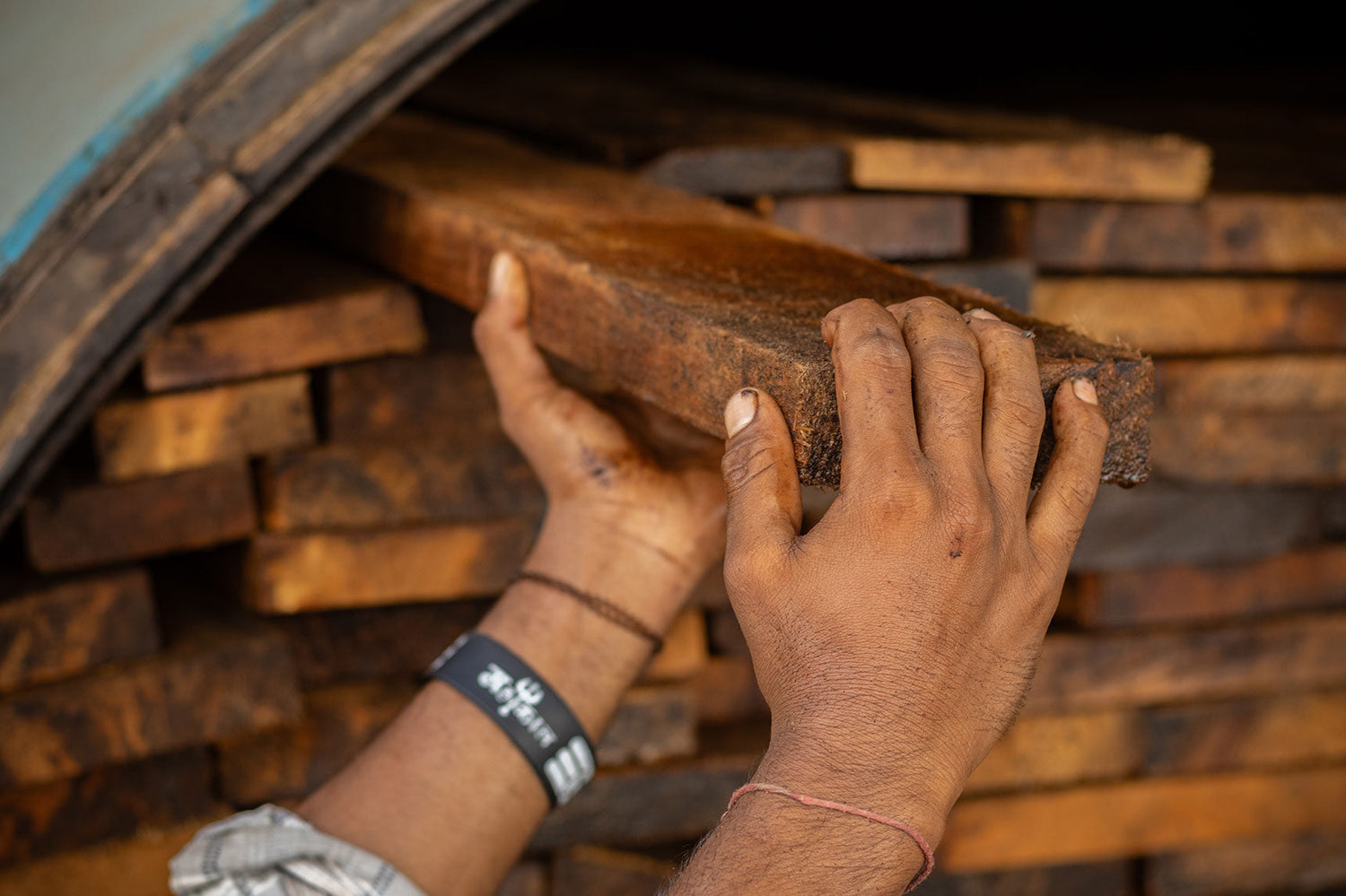 Indiase vakman kiest met de hand een plank mangohout in het atelier in Jodhpur. Indian artisan hand-selecting a plank of mango wood in the Jodhpur workshop.